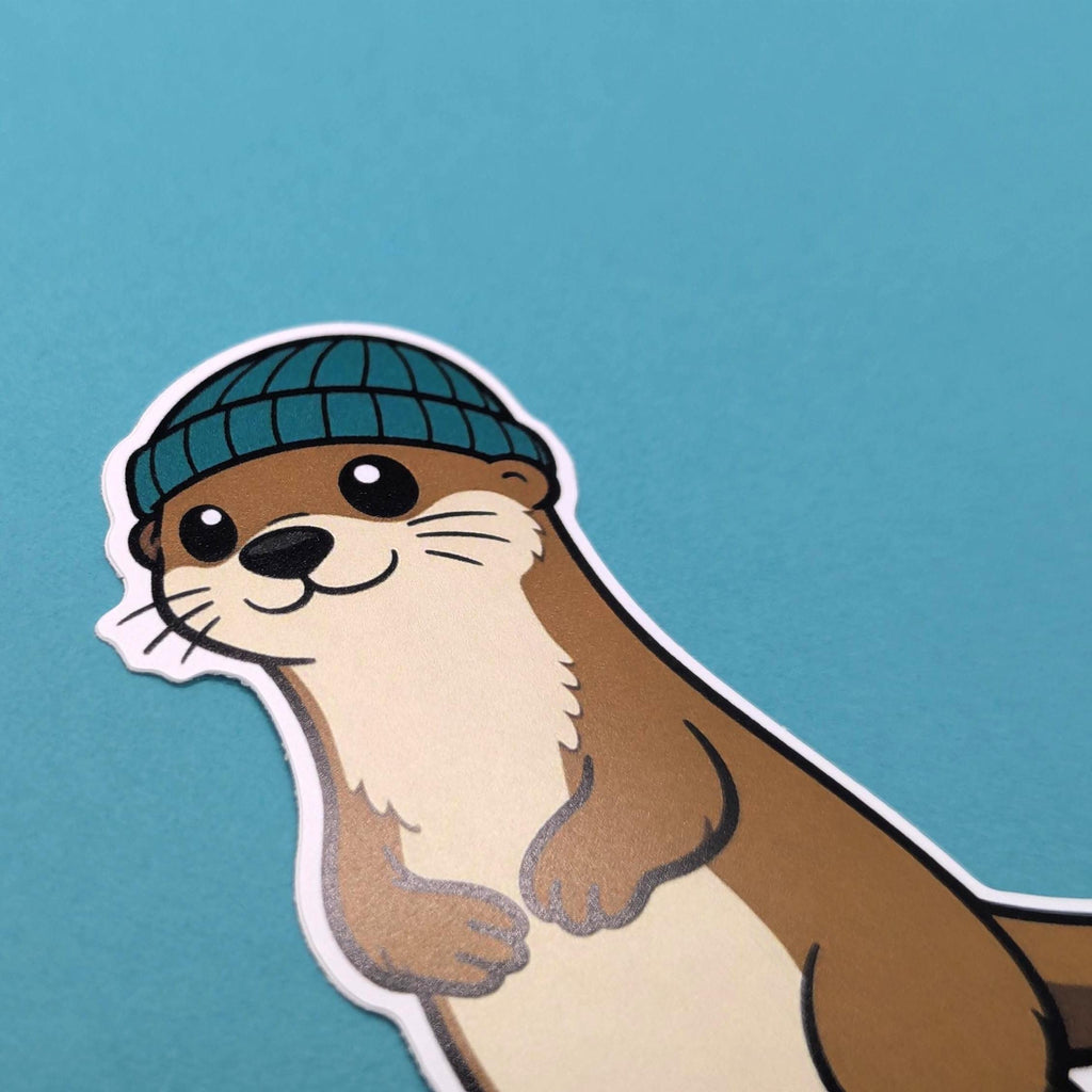 Sticker of an otter wearing a blue beanie on a teal background