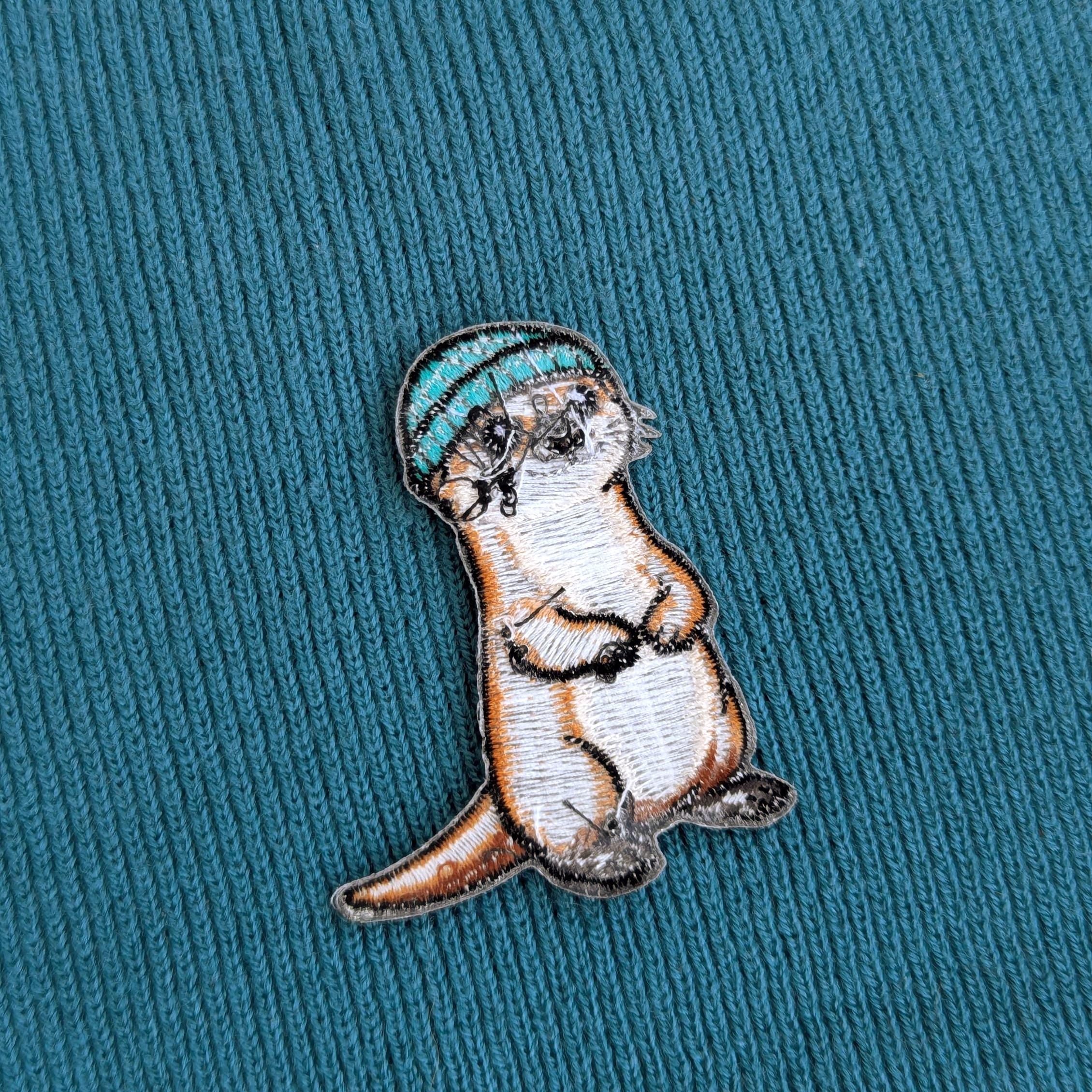 Back of mbroidered otter patch on a teal fabric background