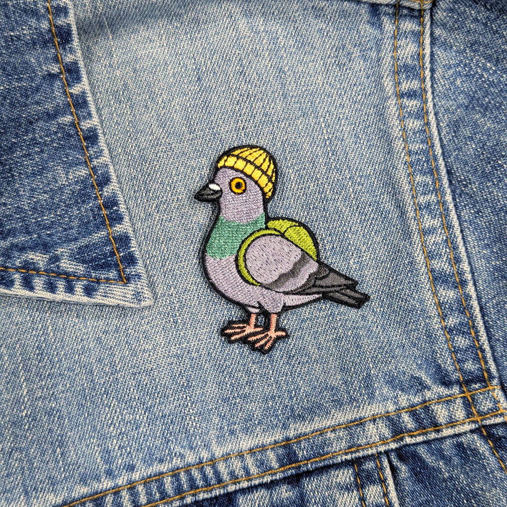 Embroidered pigeon patch on a denim background