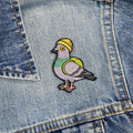 Embroidered pigeon patch on a denim background