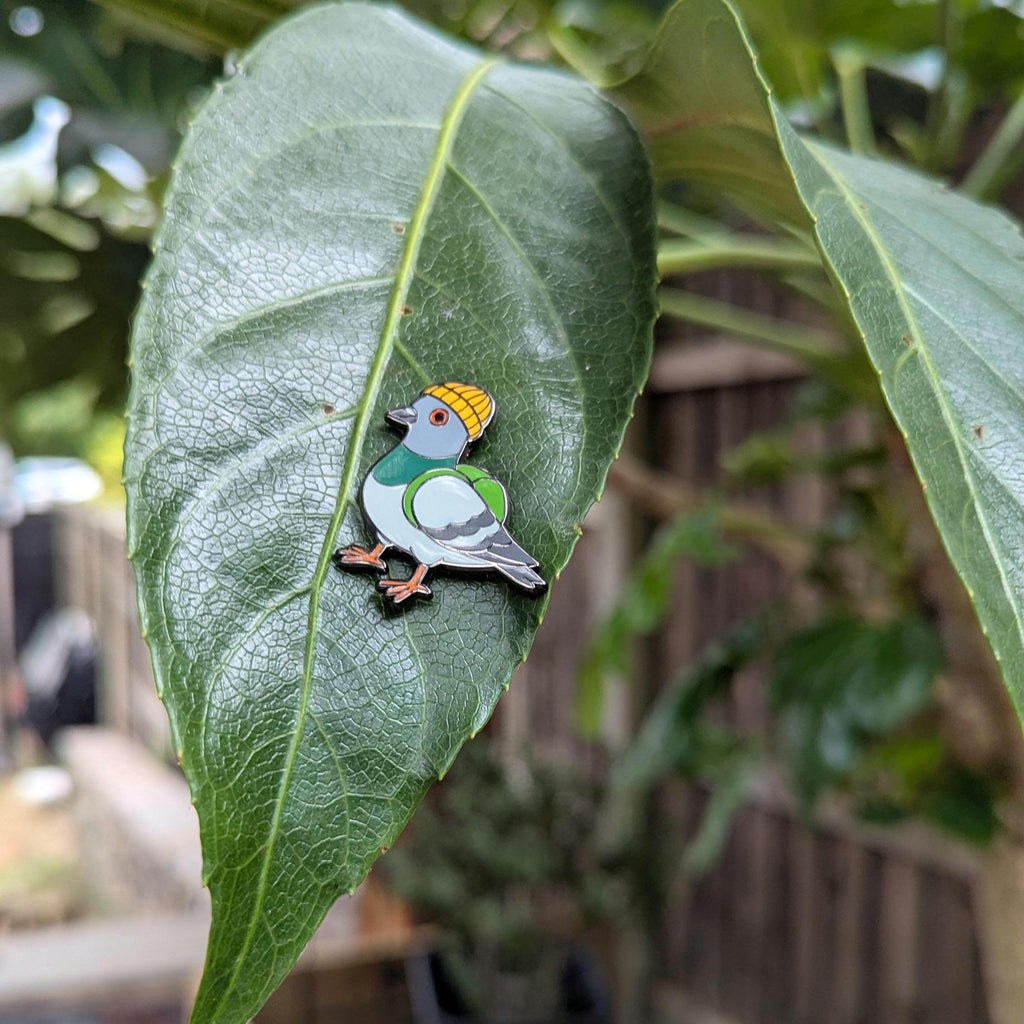 urban pigeon pin on a green leaf with a blurred outdoor background