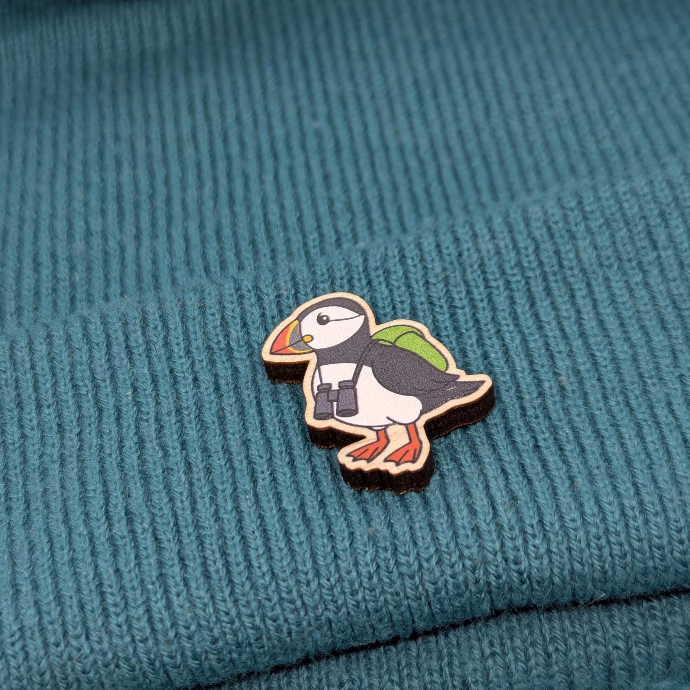 Puffin sustainable wooden pin on a textured teal fabric background