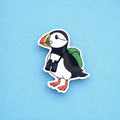 Puffin fridge magnet with a backpack and binoculars on a blue background