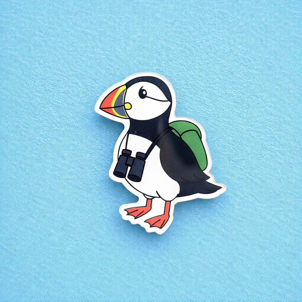 Puffin fridge magnet with a backpack and binoculars on a blue background