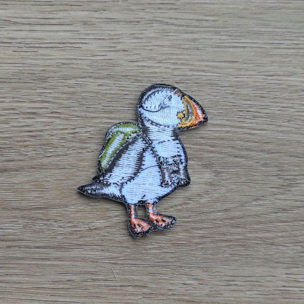Embroidered patch of a puffin back on a wooden surface