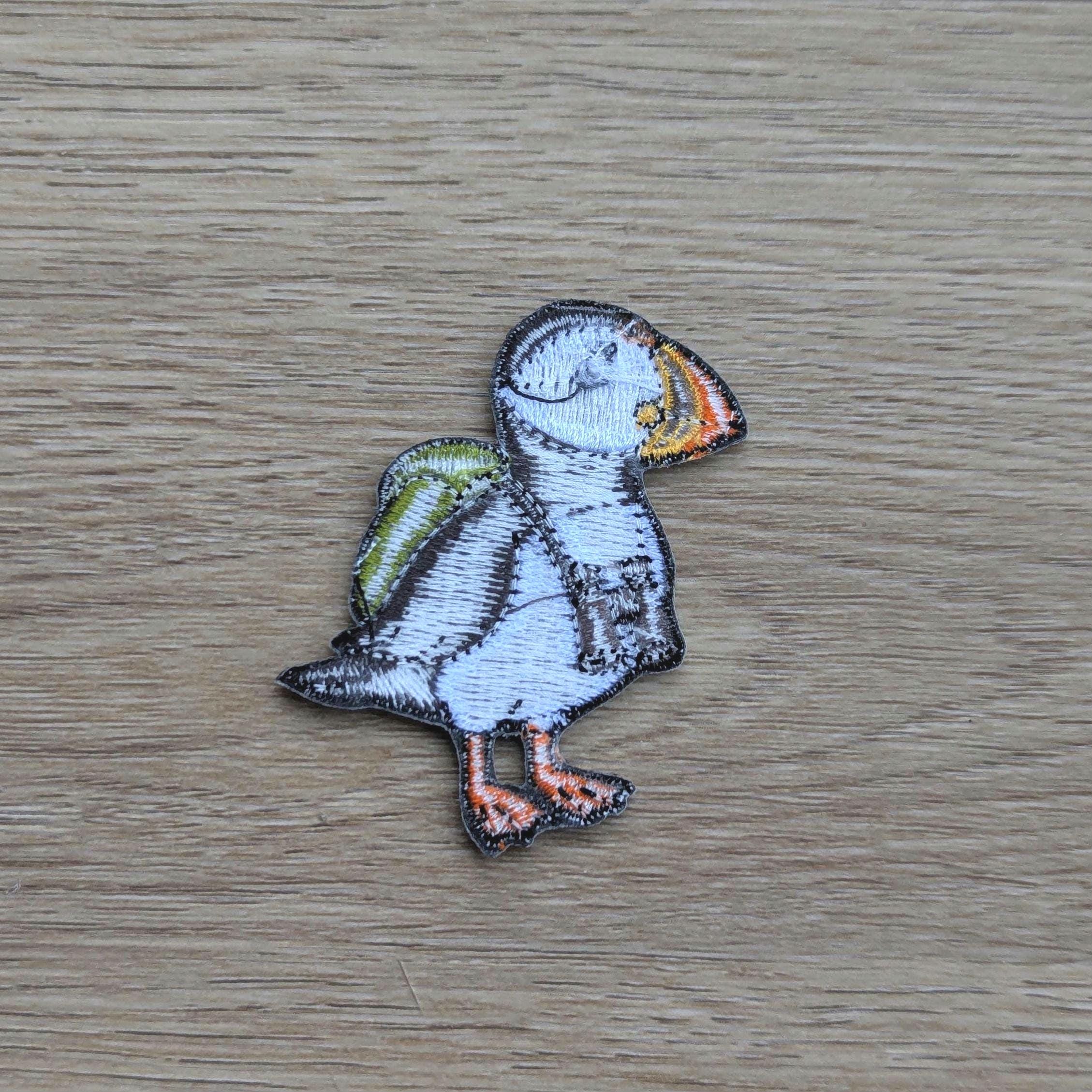 Embroidered patch of a puffin back on a wooden surface