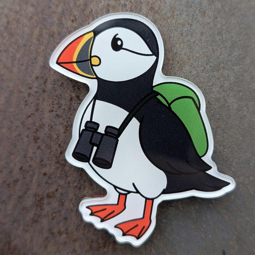 Puffin fridge magnet with a backpack and binoculars on a textured surface