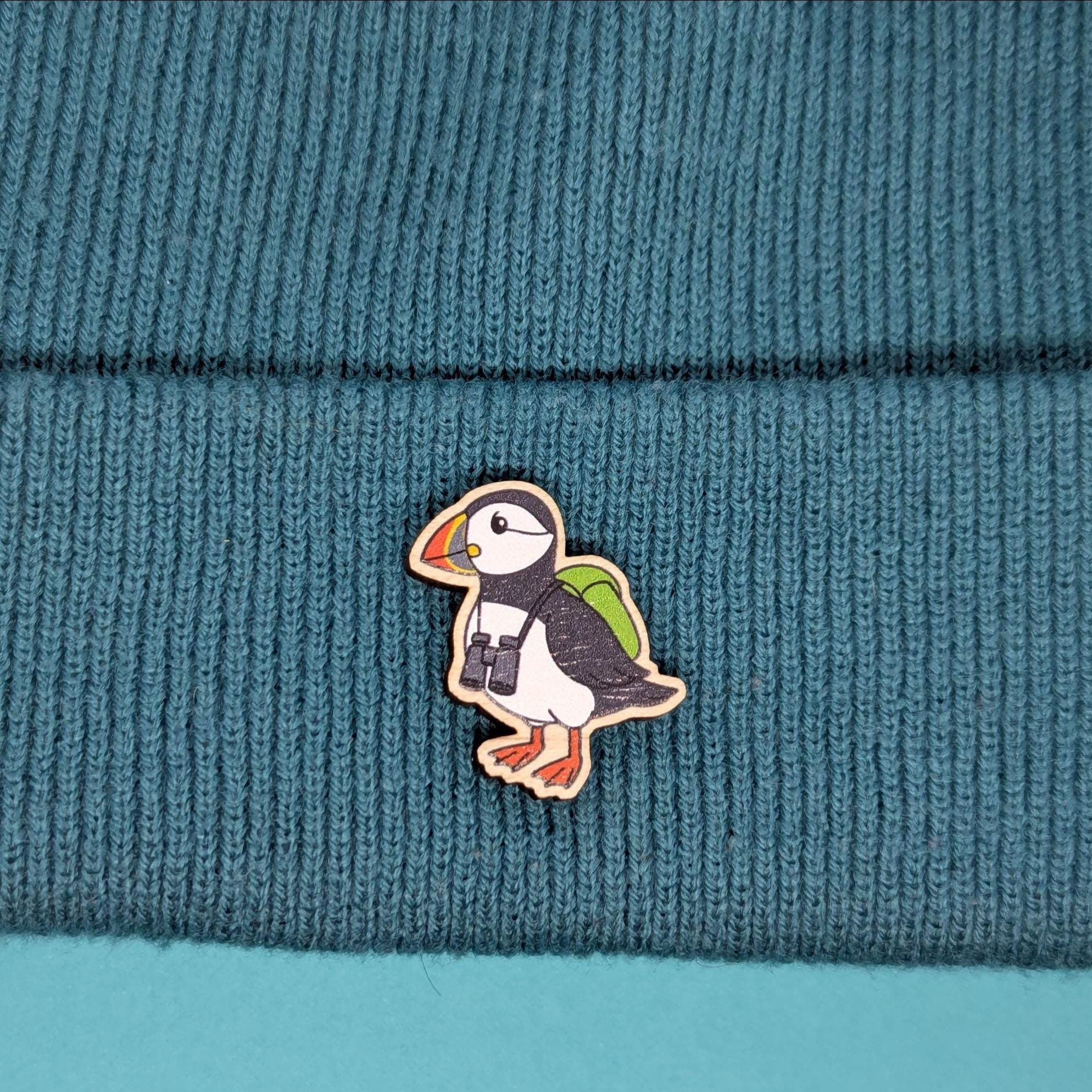 Puffin wooden pin on a teal knitted fabric background