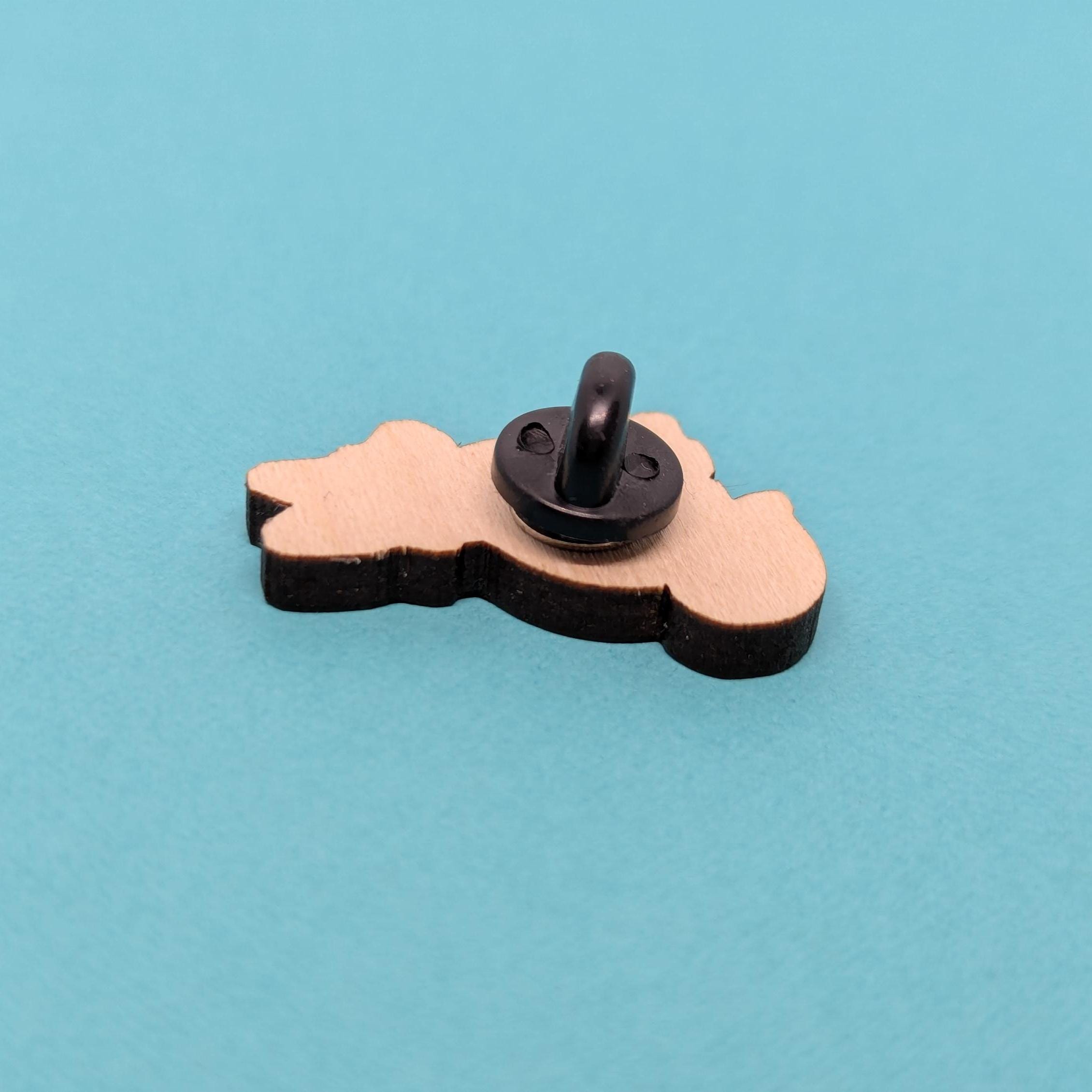 back of red fox wooden pin with a black handle on a blue background