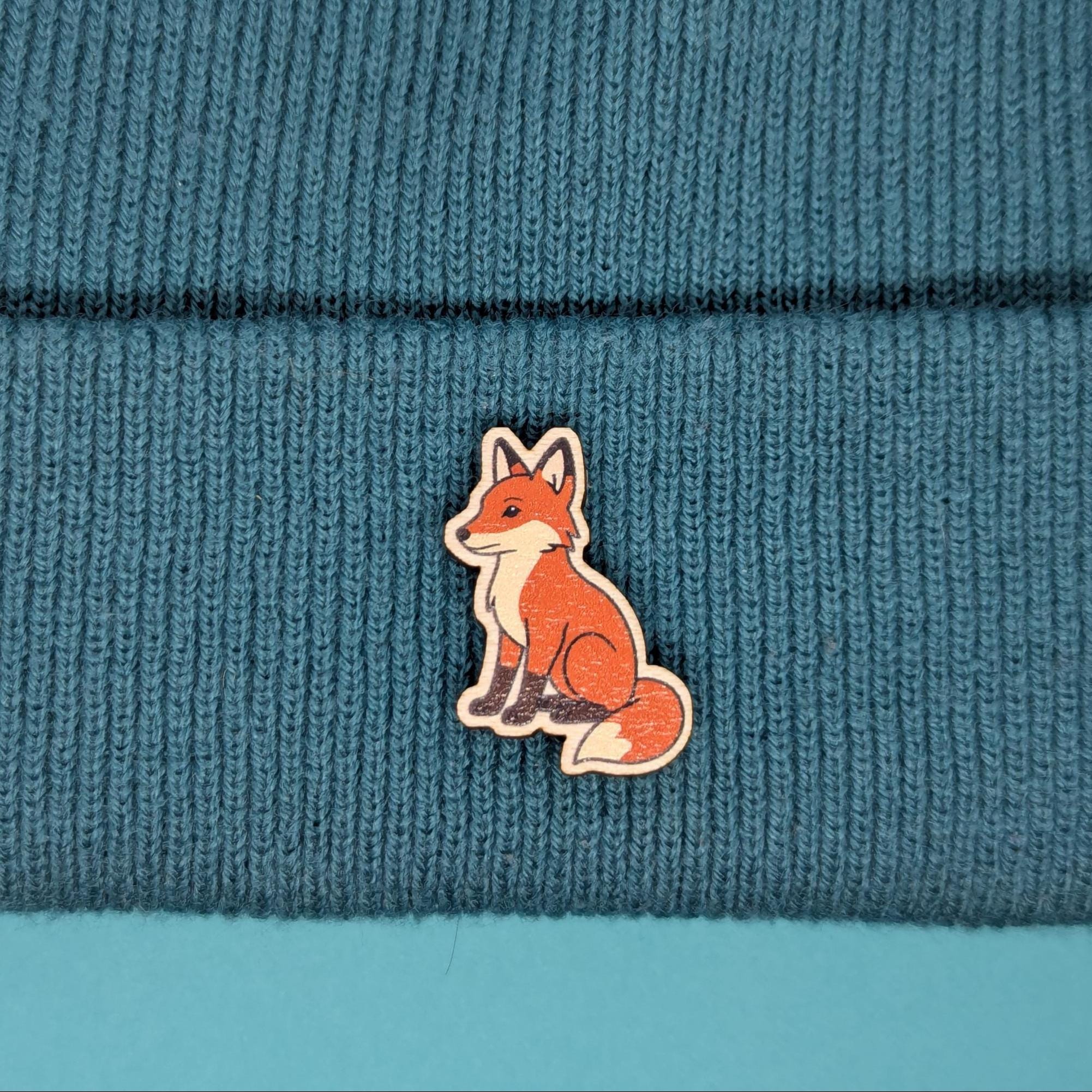 Red fox wooden pin on a blue knitted fabric background