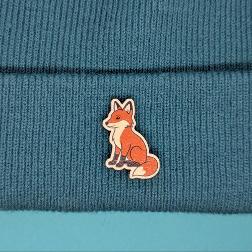 Red fox wooden pin on a blue knitted fabric background