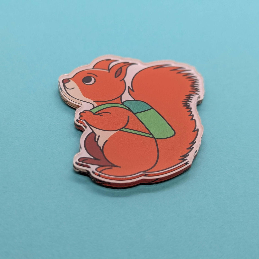 Fridge magnet of a red squirrel with a green backpack on a blue background