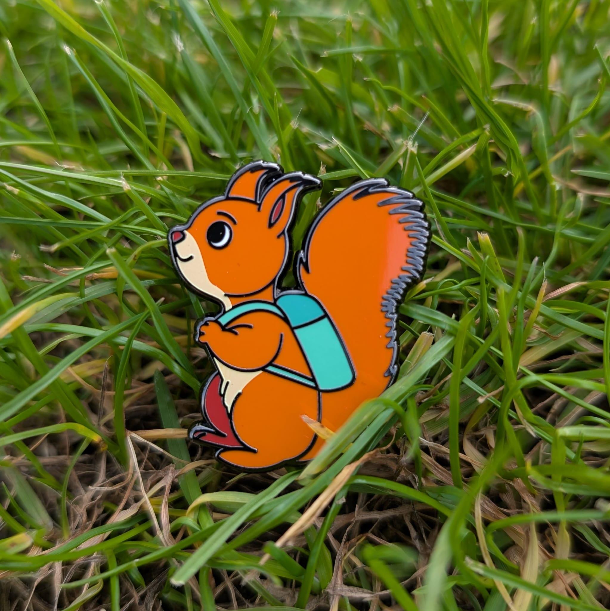 Squirrel with a backpack pin on grass