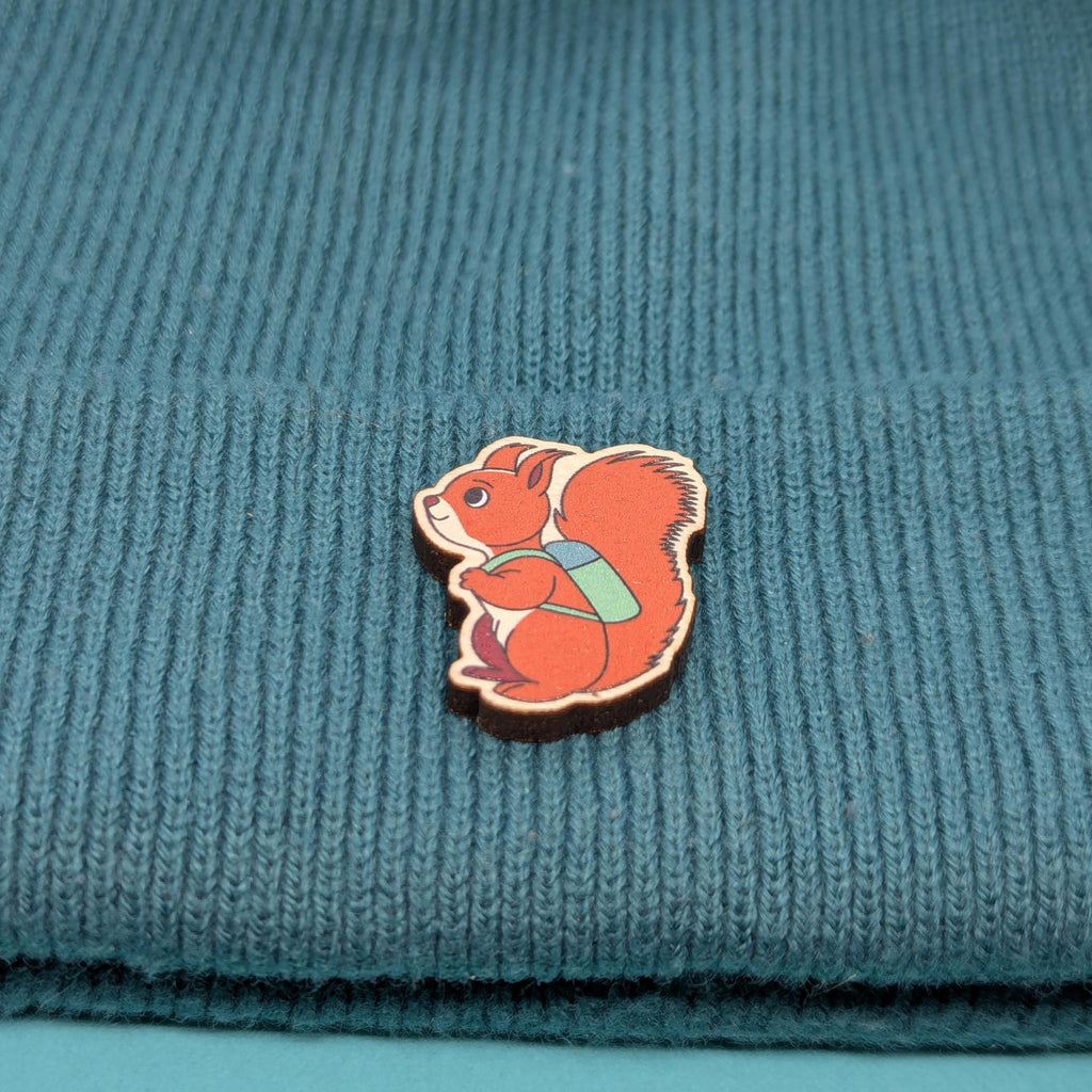 Wooden pin of a red squirrel on a blue knitted fabric