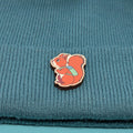 Wooden pin of a red squirrel on a blue knitted fabric