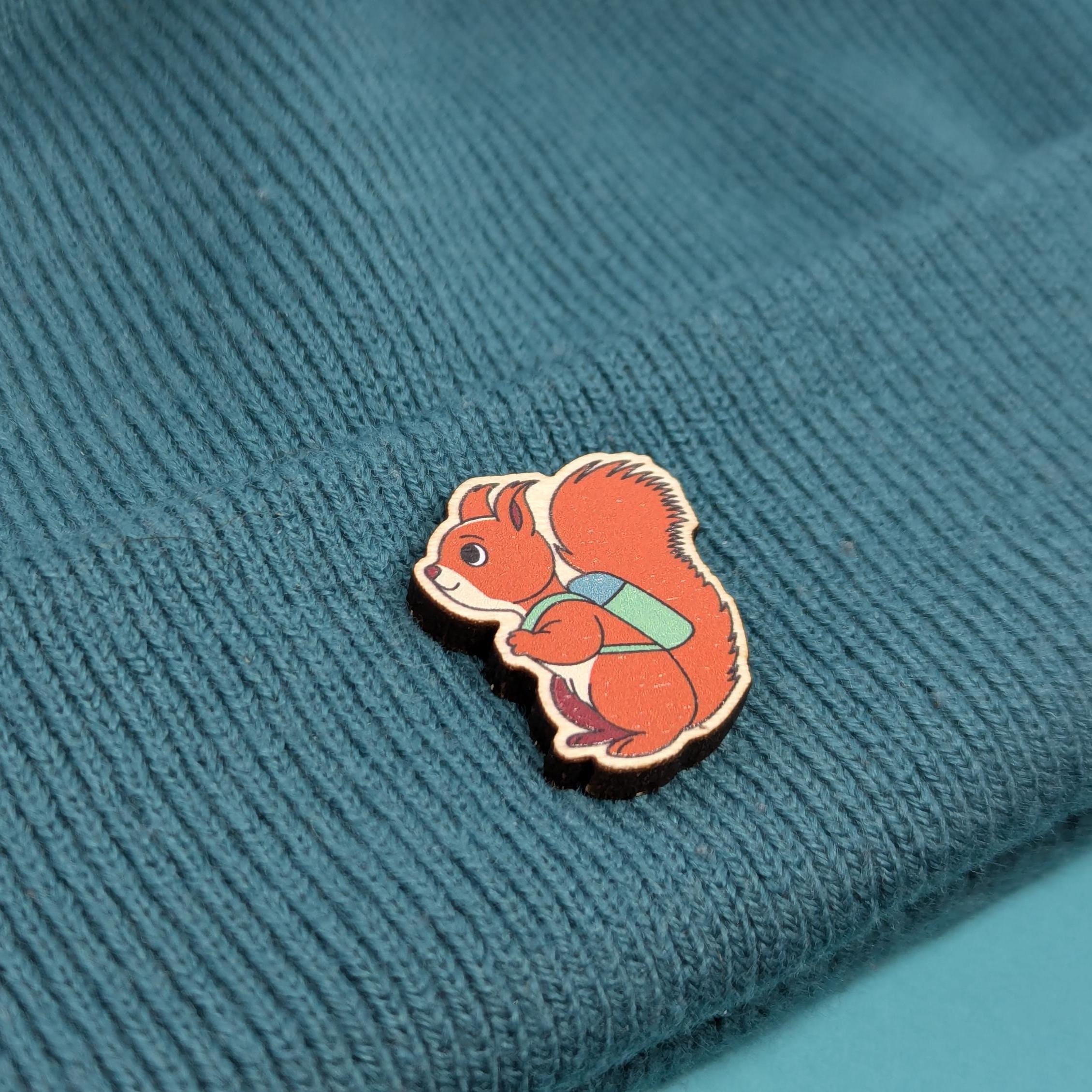Red squirrel wooden pin on a textured blue fabric background