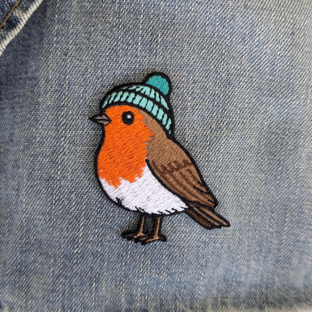 Embroidered robin patch with a blue beanie on denim fabric