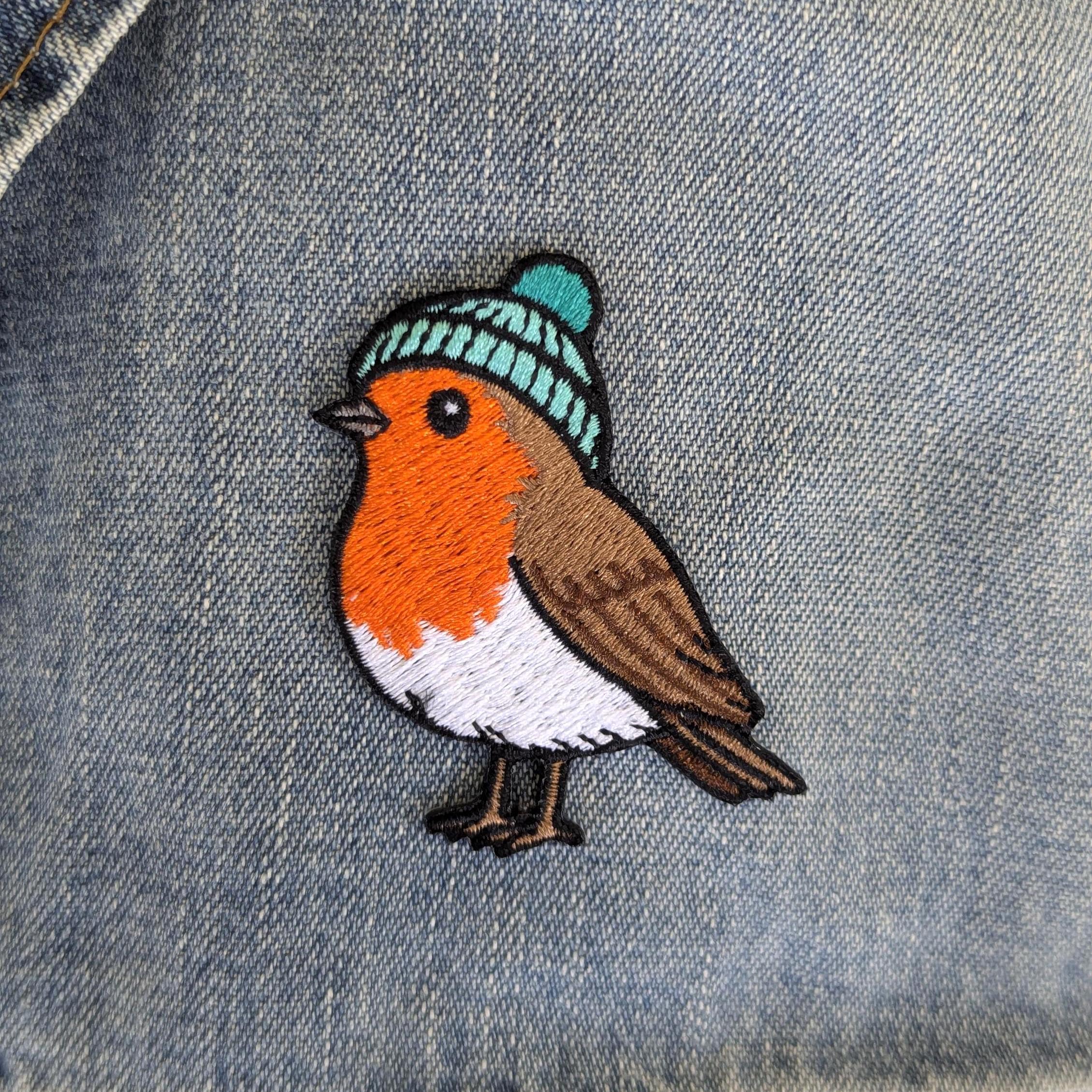 Embroidered robin patch with a blue beanie on denim fabric