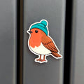 Robin bird fridge magnet with a blue beanie on a metallic surface