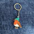 Keychain with a robin design wearing a blue hat on a denim background