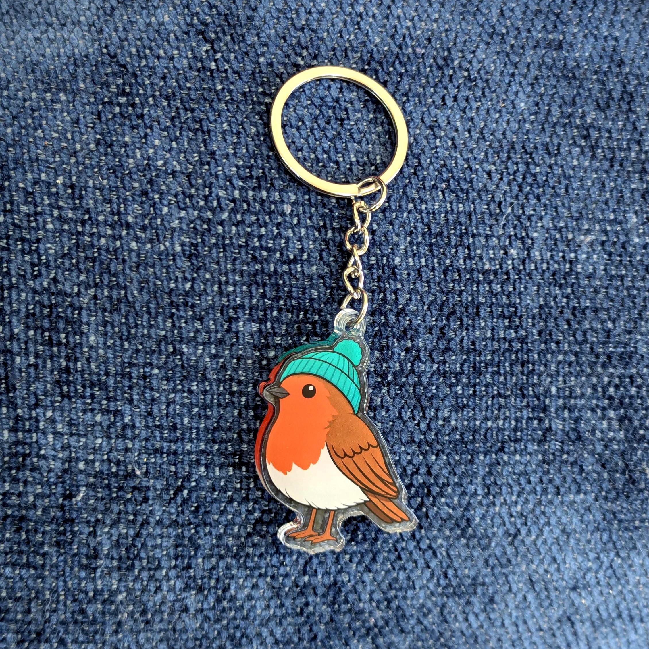 Keychain with a robin design wearing a blue hat on a denim background