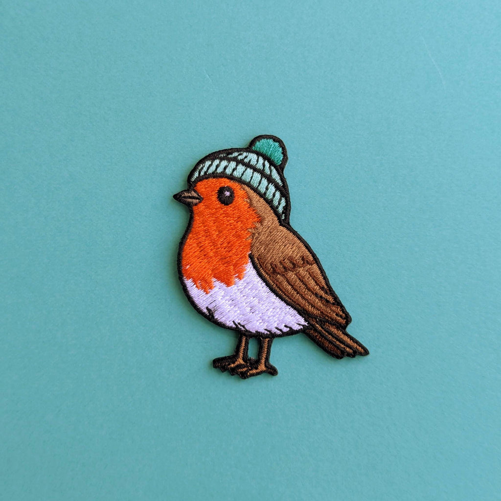 Embroidered patch of a robin wearing a knitted hat on a teal background