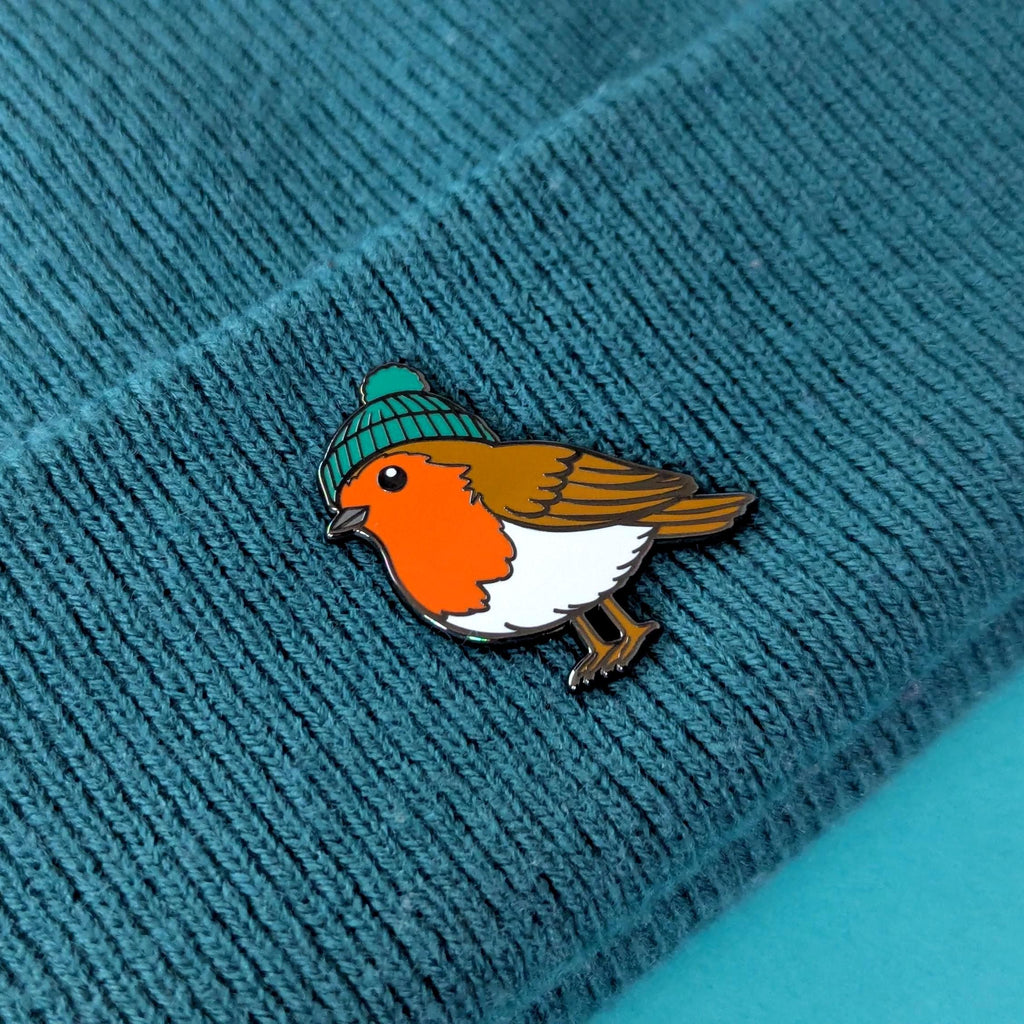 Bird pin with a green beanie on a textured blue surface