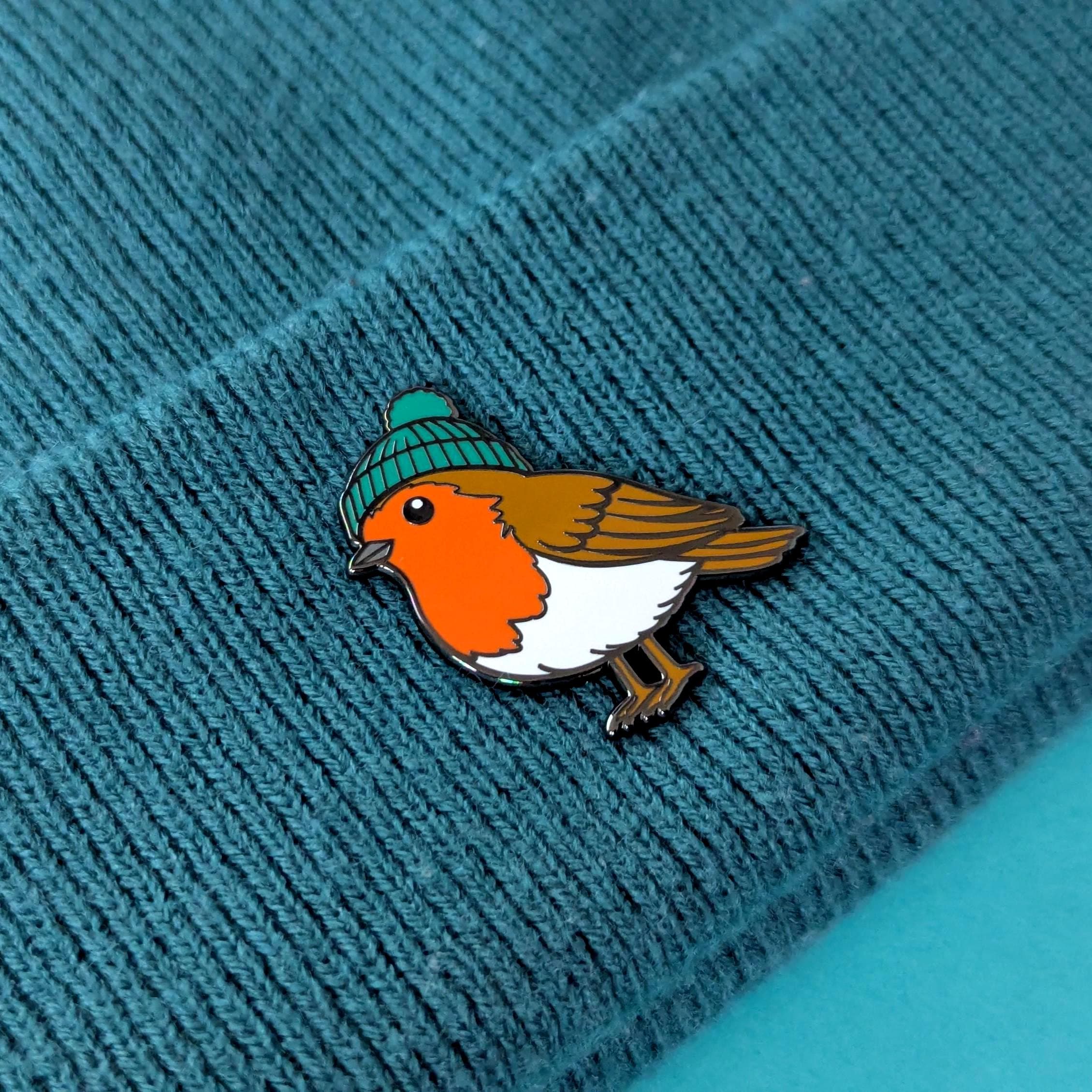 Bird pin with a green beanie on a textured blue surface