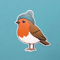 Sticker of a robin wearing a blue knitted hat on a teal background