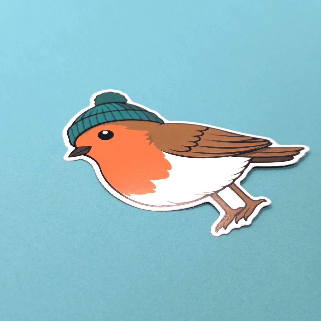 Sticker of a robin wearing a green beanie on a light blue background