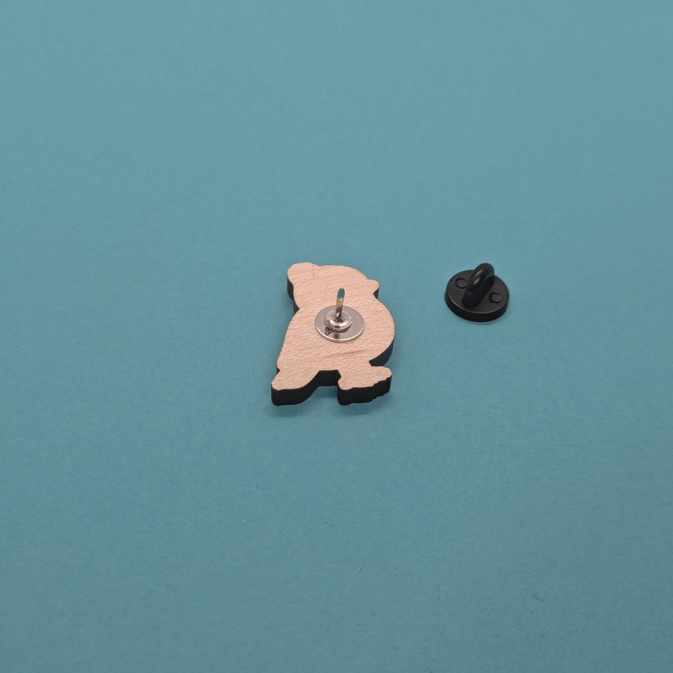 Back view of wooden robin pin badge with a black rubber pin back