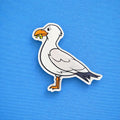 Cartoon seagull fridge magnet with a stolen chip on a blue background