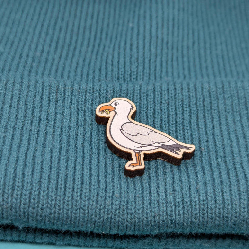 Seagull wooden pin on a teal knitted fabric