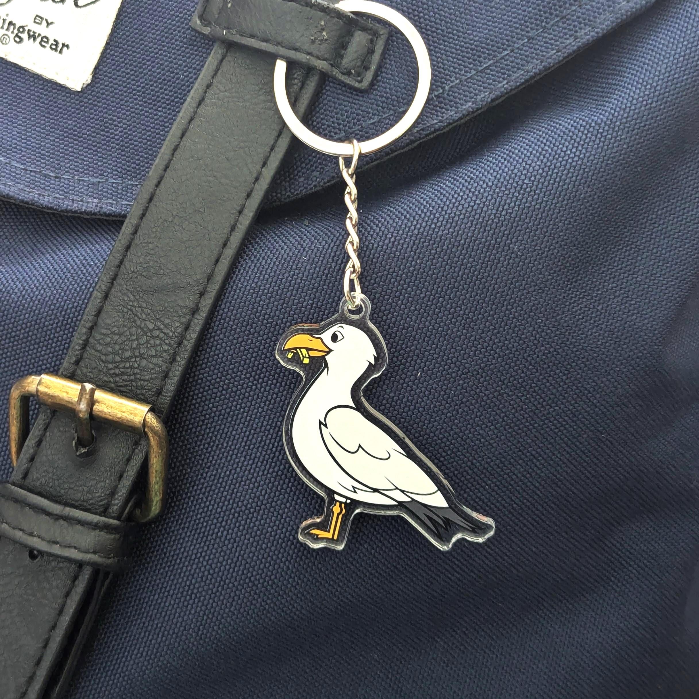 Seagull keychain attached to a dark blue bag with a strap.