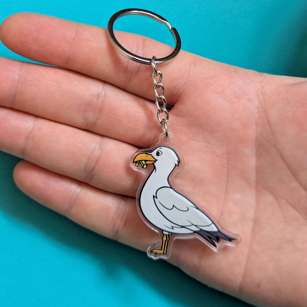 Seagull keychain held in a hand against a blue background