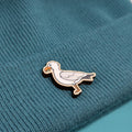 Seagull wooden pin on a textured teal fabric background
