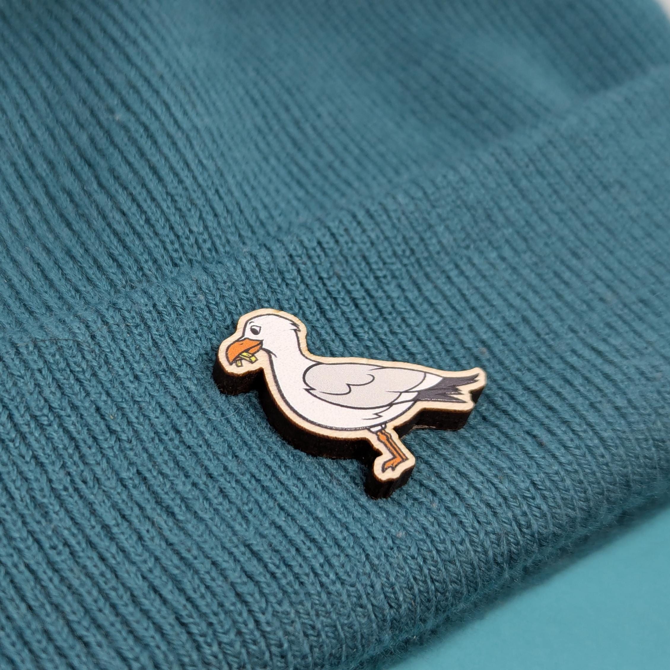 Seagull wooden pin on a textured teal fabric background