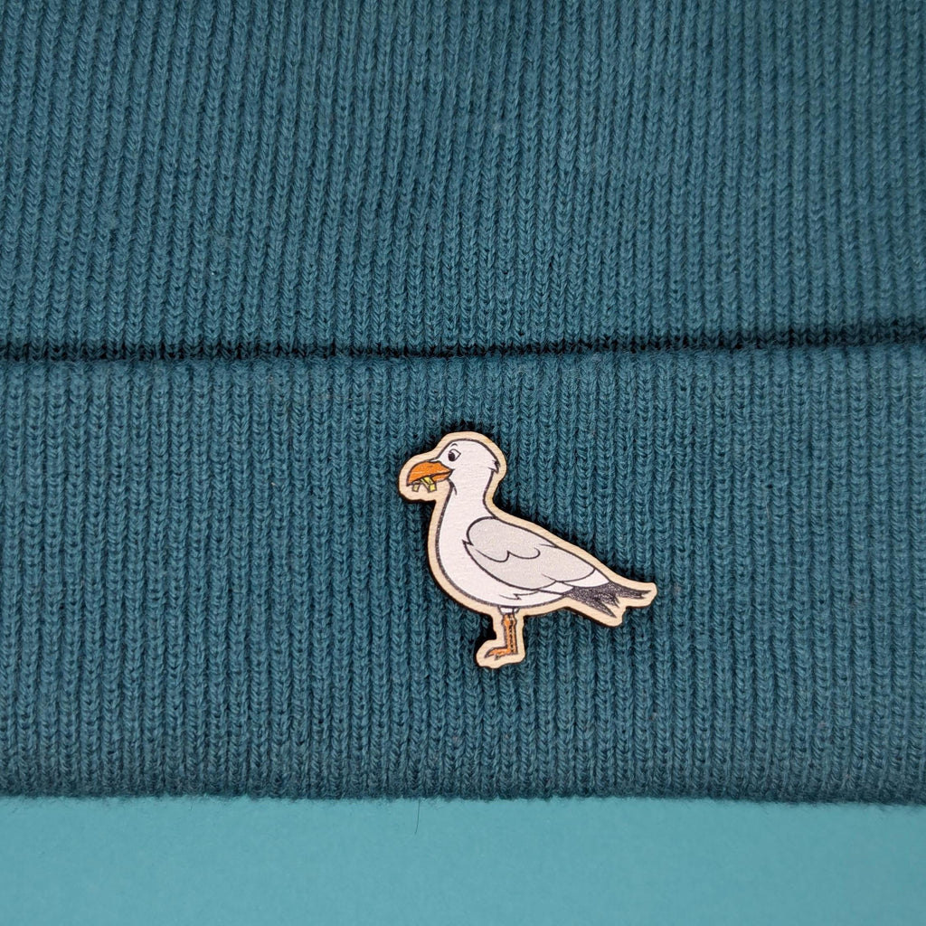 Seagull wooden pin on a textured teal fabric background