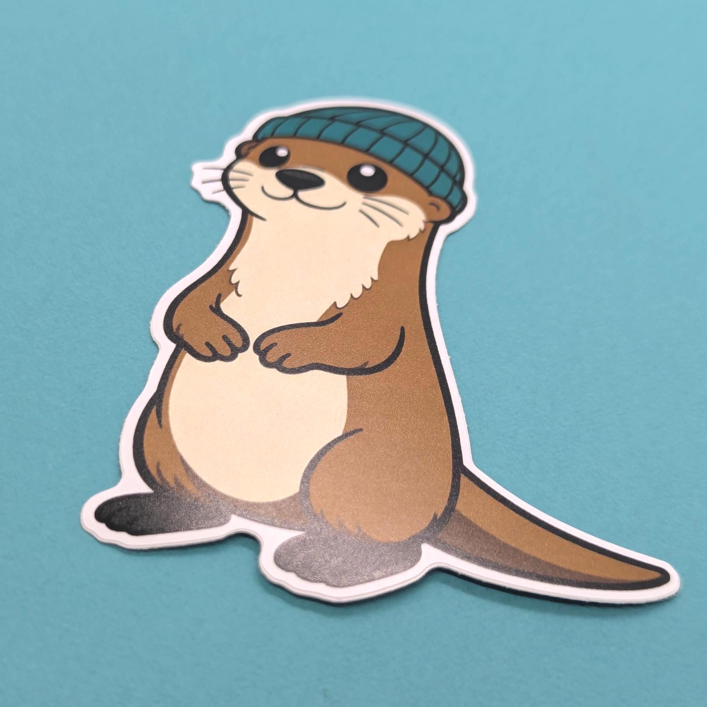 Vinyl sticker of an otter wearing a green hat on a blue background