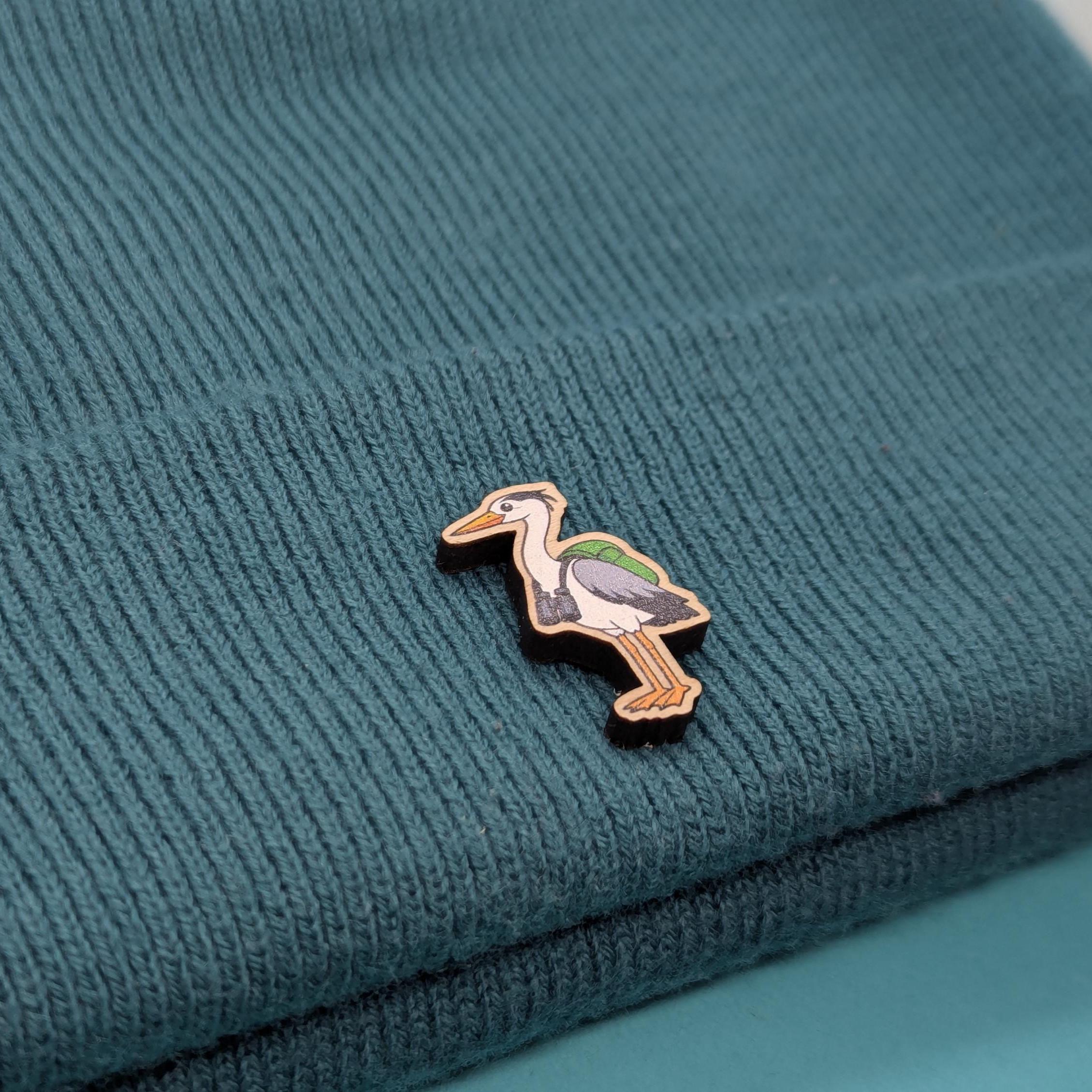 wooden heron pin on a textured teal fabric background