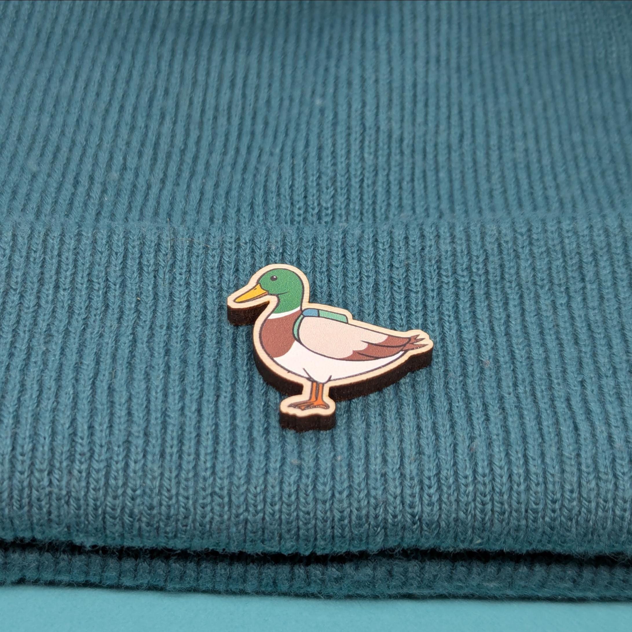 Duck wooden pin on a teal knitted fabric background