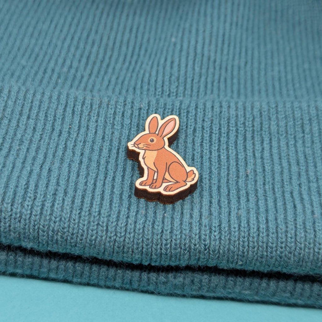 Wooden brown hare pin on a textured blue fabric background
