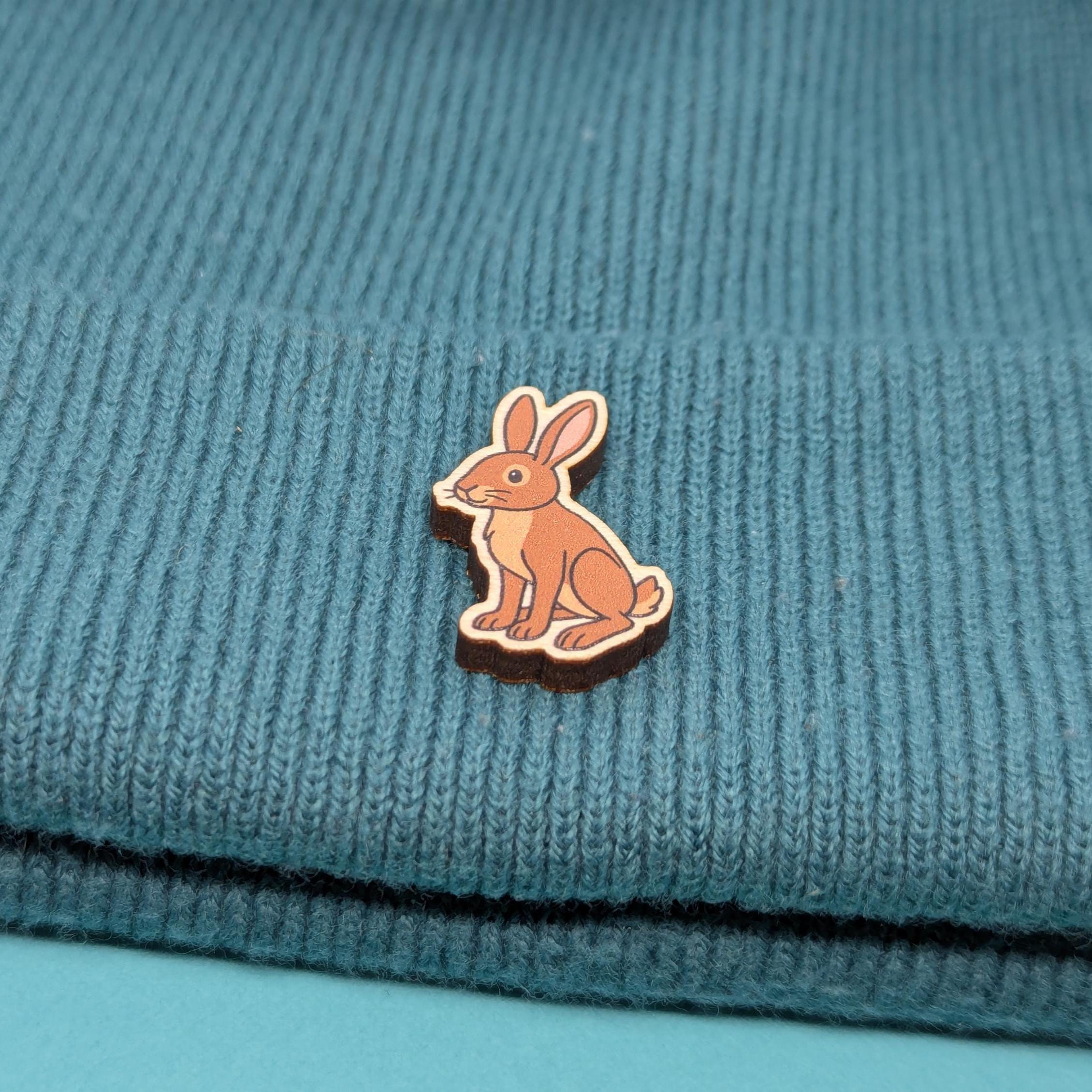 Wooden brown hare pin on a textured blue fabric background