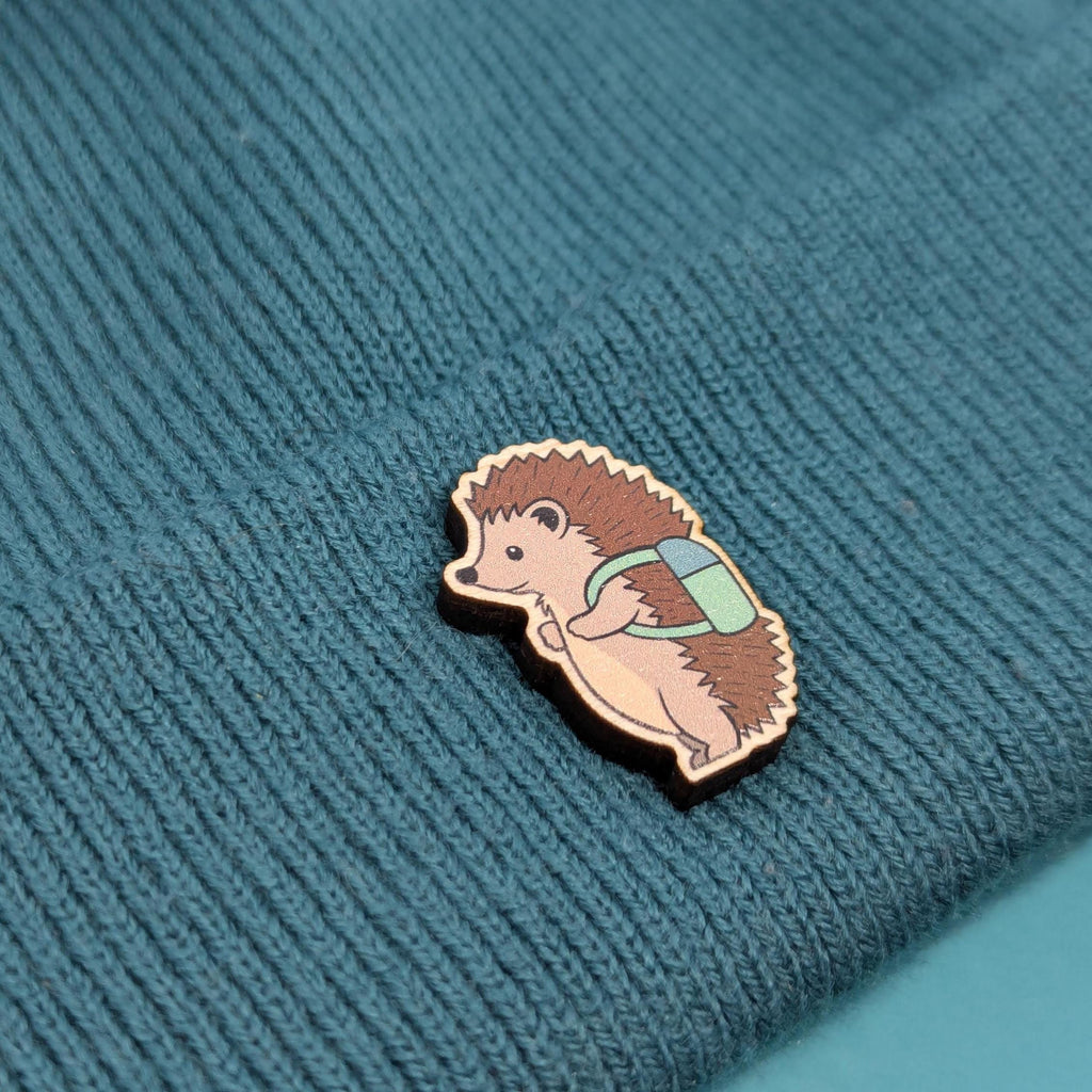 Hedgehog wooden pin on a textured teal fabric background