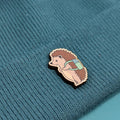 Hedgehog wooden pin on a textured teal fabric background