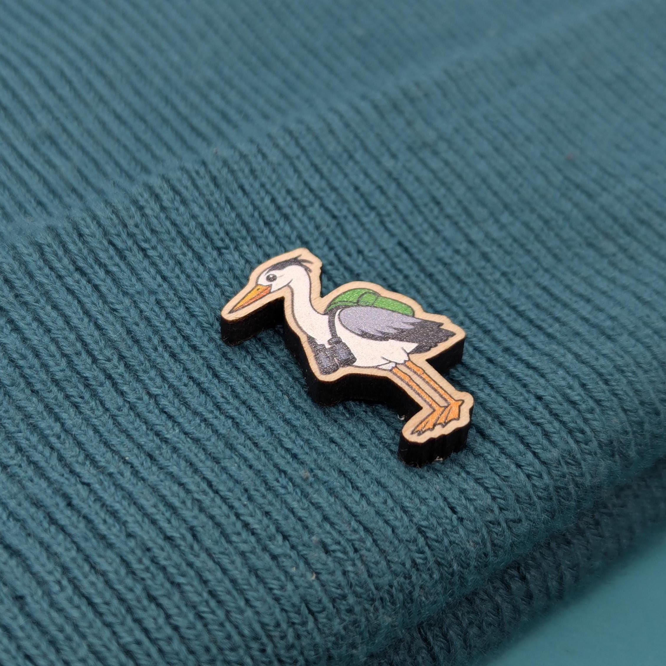 Wooden heron pin on a textured teal fabric background