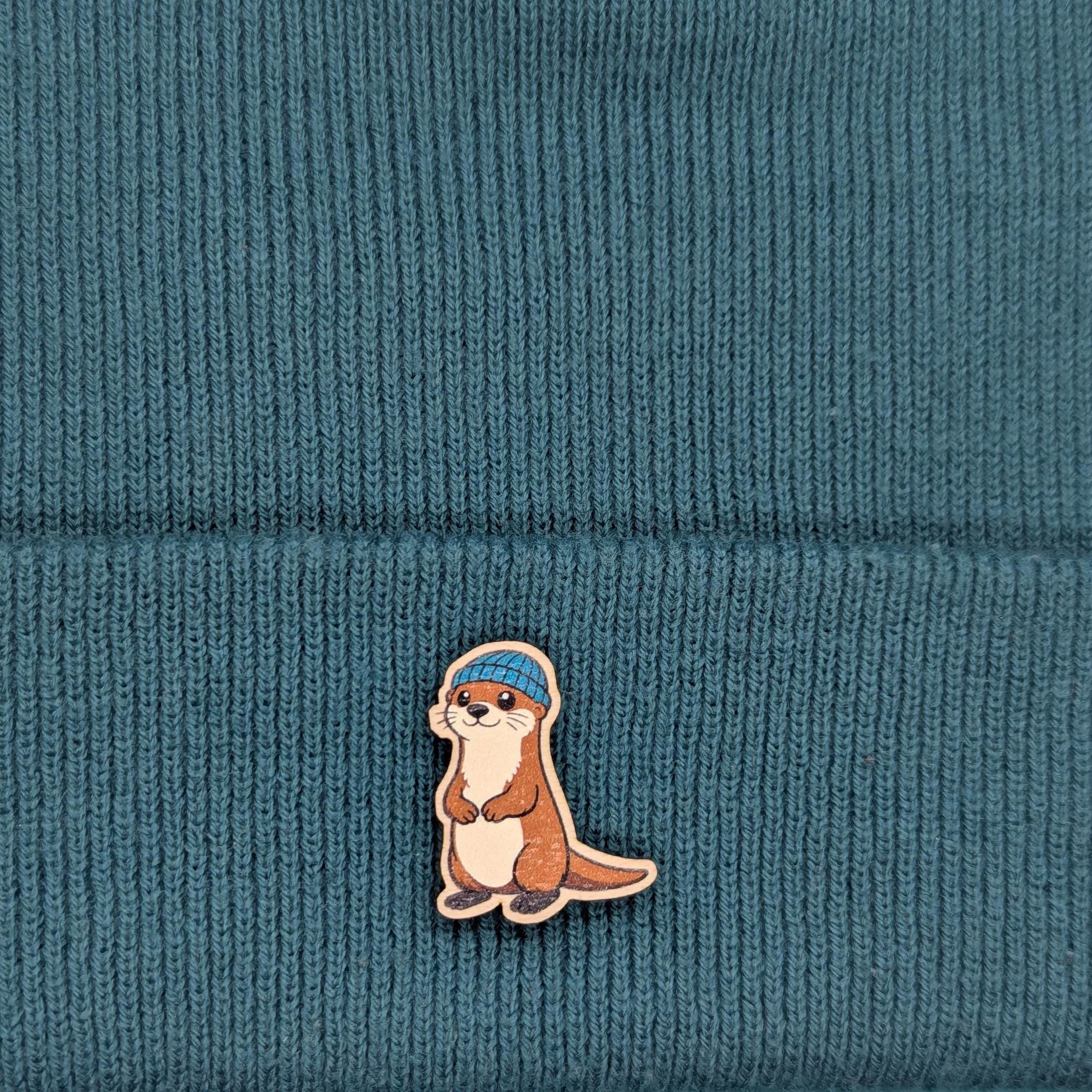 wooden otter pin on a beanie hat