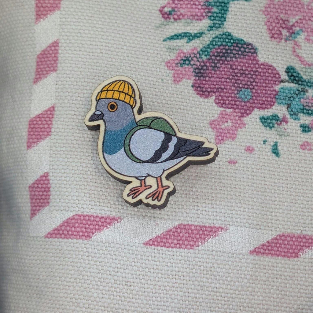 Wooden pin of pigeon wearing a yellow hat on a floral fabric background