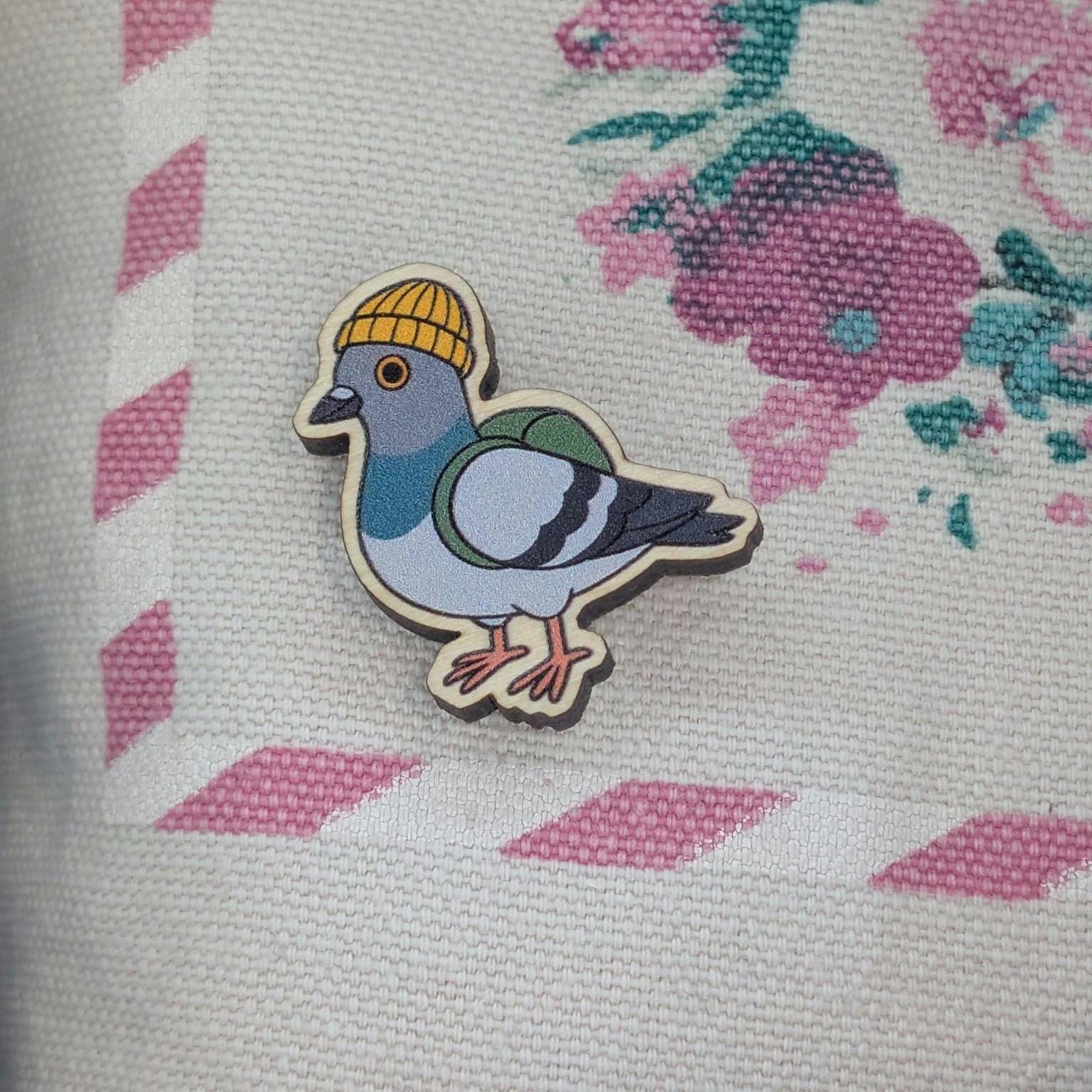 Wooden pin of pigeon wearing a yellow hat on a floral fabric background