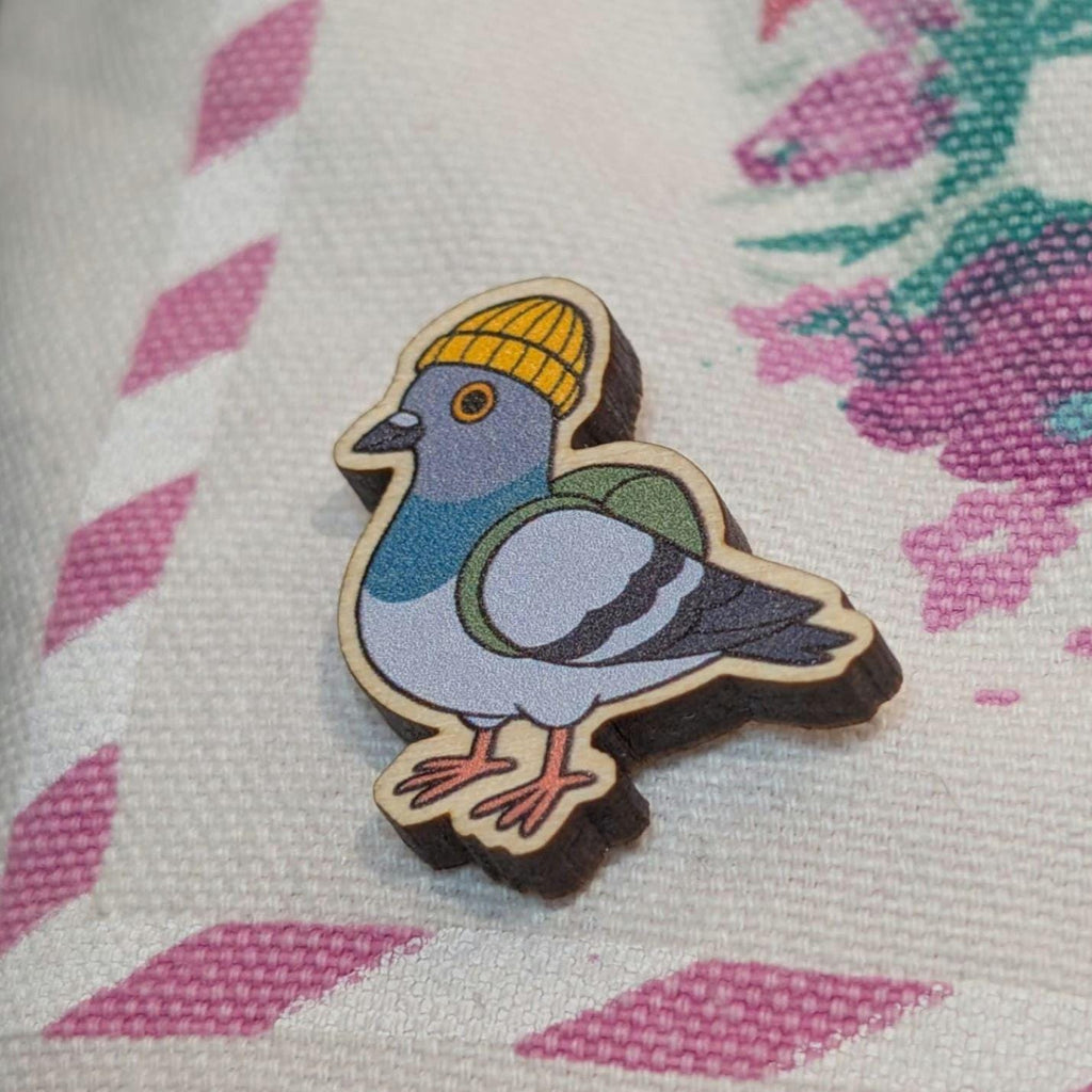 Wooden pigeon pin with a yellow beanie on a textured fabric background